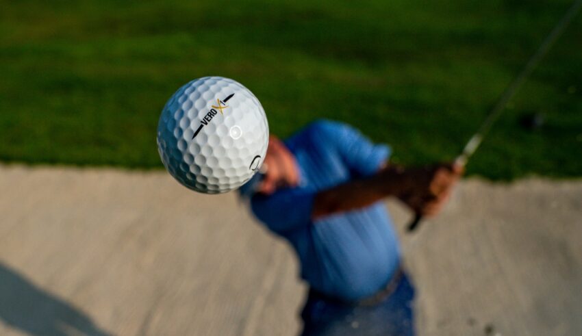 En man som slår en golfboll ur en bunker